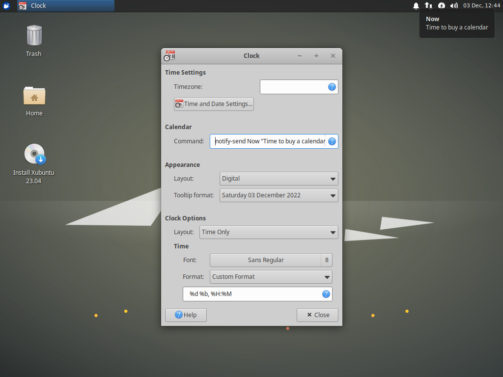 The Xubuntu 23.04 desktop is displayed. The Xfce Panel Clock preferences dialog is open and shows the new Calendar Command setting. The command has been set to show a notification with the message "Now, Time to buy a calendar".